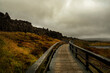 dramatic landscape with wooden bridge and gloomy rocks. Iceland. Fault.