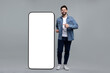 © New Africa - Man pointing at huge mobile phone with empty screen on grey background. Mockup for design