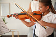© New Africa - Young woman teaching little girl to play violin indoors