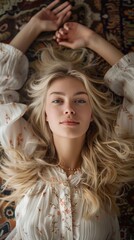 Wall Mural - Top view of young woman is lying on the floor and looking at camera.