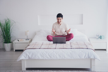 Canvas Print - Photo of positive glad man sitting on bed working from home speaking vacation time white day light room indoors