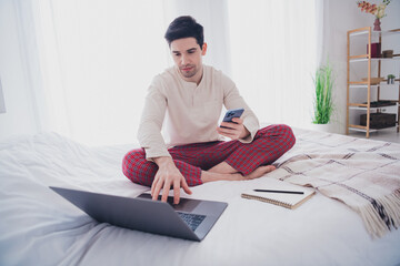 Poster - Photo of attractive nice cheerful man working from home with netbook sitting on soft bed in white room indoors