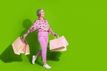 Poster - Full length photo of positive excited lady dressed pink shirt rising shoppers empty space isolated green color background