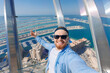 Young man tourist make selfie photo on background skyscrapers in Dubai on view point. UAE business tourism for cryptocurrency concept