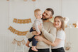 Toddler holding stuffed toy with joyful expressions in celebration setting, surrounded by family and decorations for memorable. First birthday of little happy boy