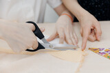 Fototapeta  - Dressmaker girl child cutting fabric with scissors on sewing master class in school