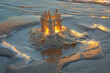 A solitary sandcastle standing tall against the backdrop of the setting sun, its turrets casting long shadows on the sand.