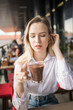 Gen z blonde woman drinks hot chocolate in summer cafe. Tasty beverage and break concept. Generation z people
