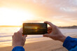 © castellanos80 - Hands taking photos with a phone at sunset. Galicia Spain.