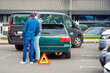 Car accident in parking lot, men set up red warning triangle after collision in parking area. Parking accident due reckless and distracted driving on tight parking lot. .
