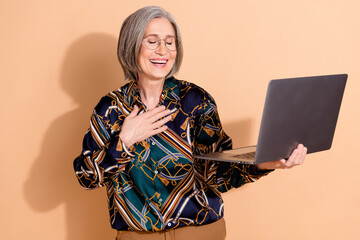 Sticker - Photo of funny good mood person wear print blouse in glasses holding laptop palm on chest laughing isolated on beige color background