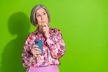 Poster - Photo of doubtful unsure lady pink shirt chatting modern device looking empty space isolated green color background