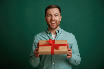 Wall Mural - Little gift box in hands. Man is standing against background in the studio