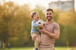 © standret - Standing, holding soccer ball. Happy father with son are having fun on the field at summertime