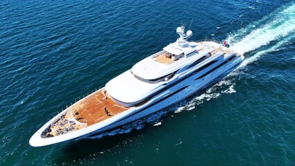 Wall Mural - Aerial drone tracking photo of beautiful modern super yacht with wooden deck and helipad cruising in high speed deep blue open ocean sea