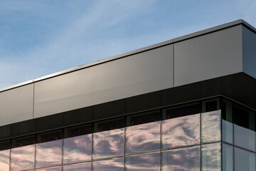 Wall Mural - The exterior wall of a contemporary commercial style building with aluminum metal composite panels and glass windows. The futuristic building has engineered diagonal cladding steel frame panels.