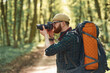 Photographer with camera. Bearded man is in the forest at daytime
