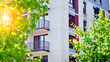 Modern residential building with new apartments in a green residential area. Eco architecture. Green tree and new apartment building. The harmony of nature and modernity.