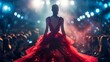 © Prostock-studio - A model in a red dress commands the runway during a fashion event with a vibrant, illuminated backdrop.