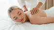 © Prostock-studio - A woman lying face down on a massage table at a spa, receiving a back massage from a massage therapist, panorama