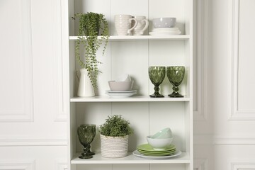 Wall Mural - Different clean dishware and houseplants on shelves in cabinet indoors