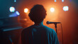 © Maksym - The camera captures the young artist from behind, their form bathed in the soft glow of studio lights, as they stand before the microphone, their presence commanding yet vulnerable