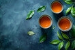 Three cups of tea with green leaves on a textured blue background, flat lay, copy space