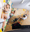 Focused young girl ascending colorful holds on indoor bouldering wall, demonstrating physical strength, technical skills, and determination while practicing sport climbing