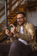 © Miljan Živković - Adult man with eyeglasses play video games on his phone at home
