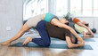 © JackF - Young married couple meditate together in various yoga poses during group training in the gym