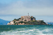 Explore rugged Alcatraz Island in San Francisco Bay, California, USA. Iconic federal prison buildings and rocky shores set against a partly cloudy sky.