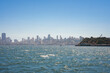 Discover the dynamic San Francisco skyline from the tranquil waters near Alcatraz Island. A mix of tall buildings creates a vibrant cityscape against the clear blue sky.