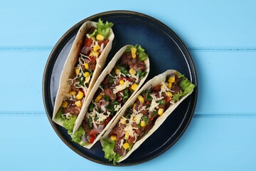 Wall Mural - Delicious tacos with meat and vegetables on light blue table, top view