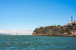Scenic view of Alcatraz Island in San Francisco Bay, California, featuring the iconic lighthouse, Golden Gate Bridge in the background, and choppy waters.