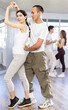 © JackF - Young couple performs an expressive salsa in bright, modern dance studio during a group class