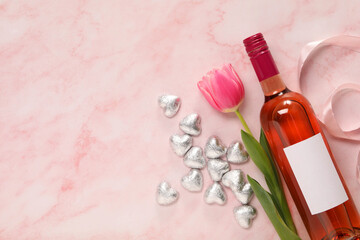 Sticker - Delicious heart shaped chocolate candies, beautiful tulip and bottle of wine on pink table, flat lay. Space for text