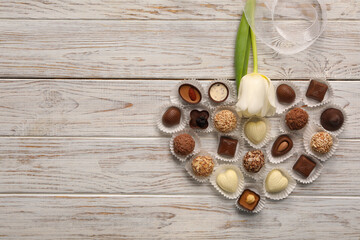 Sticker - Heart made with delicious chocolate candies and beautiful tulip on white wooden table, flat lay. Space for text