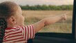 Happy family travels by car. Little girl kid enjoys family trip by car. Child, stretching his hand out of car window, laughs. Girl child looks out of car window. Child holiday emotion. Family vacation
