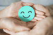 Hand holding green happy smile face paper cut, mental health assessment, child positive wellness, world mental health day, compliment day, mindful concept