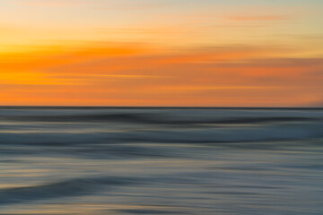 Wall Mural - Golden sunset over the Pacific ocean. Abstract seascape, motion blur, vibrant colors, copy space