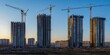 © Tida - Skyscrapers under construction with cranes at twilight - Urban skyline showing the development of modern skyscrapers under construction and towering cranes against an evening sky, symbolizing growth