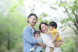 逆光の新緑の公園で遊ぶ仲良しで笑顔の日本人家族　カメラ目線　上半身のクローズアップ