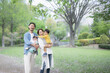 逆光の新緑の公園で遊ぶ仲良しで笑顔の日本人家族　カメラ目線の広角