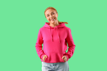 Poster - Mature woman in fuchsia hoodie on green background