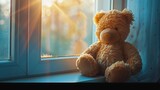 Fototapeta  - A plush teddy bear sitting on a sunlit windowsill