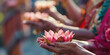 © Dmitriy - Close-up of hands holding beautifully crafted lotus offerings at a temple, with other devotees blurred in the background