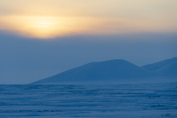 Wall Mural - Winter arctic landscape. View of the snow-covered tundra and snow-capped mountains. Cold frosty winter weather. Endless Arctic Desert. Northern nature of the polar region. Sunset. Chukotka, Russia.