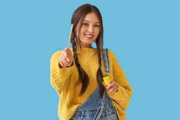 Poster - Female Asian artist with brush and paint on blue background