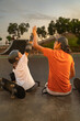 © Guillermo Spelucin - Skateboarder boy high-fiving his coach at the skate park
