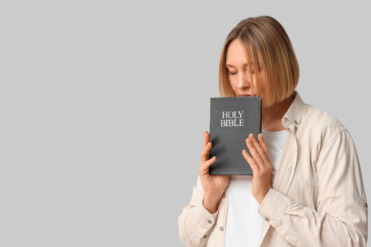 Adult woman with Holy Bible praying on white background